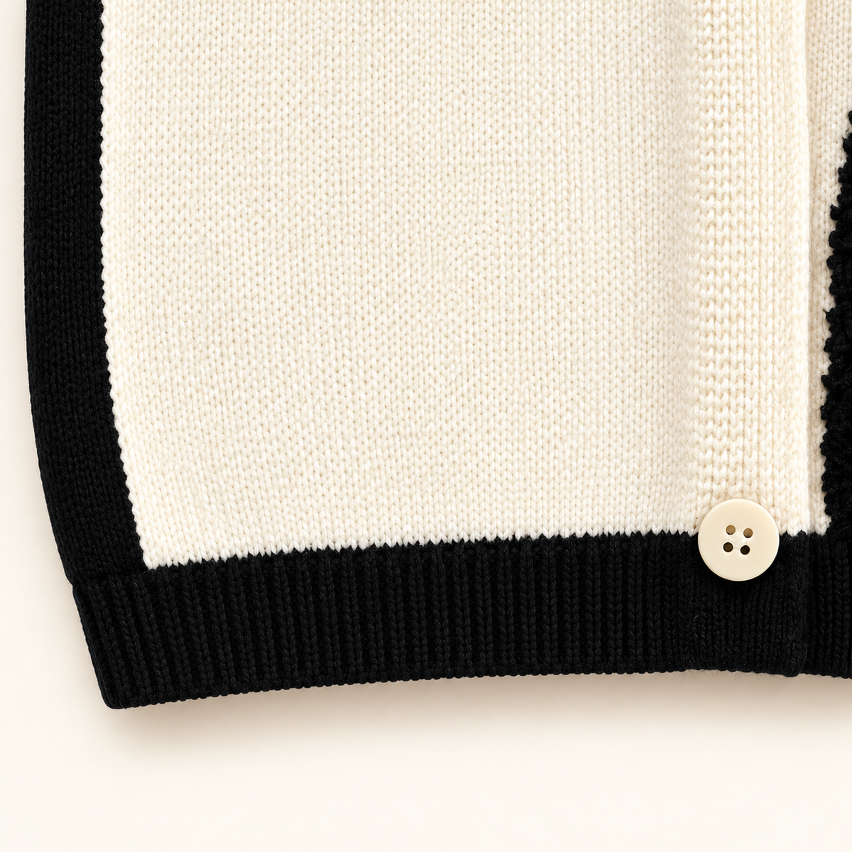 Ivory knit texture and black ribbed hem detail on cat vest