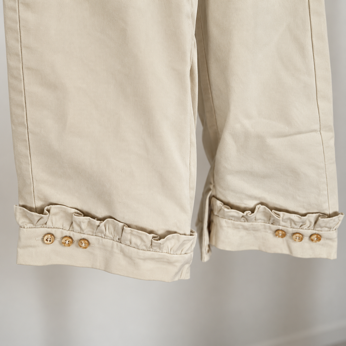 Cream trouser ruffled cuffs and three tan buttons detail.