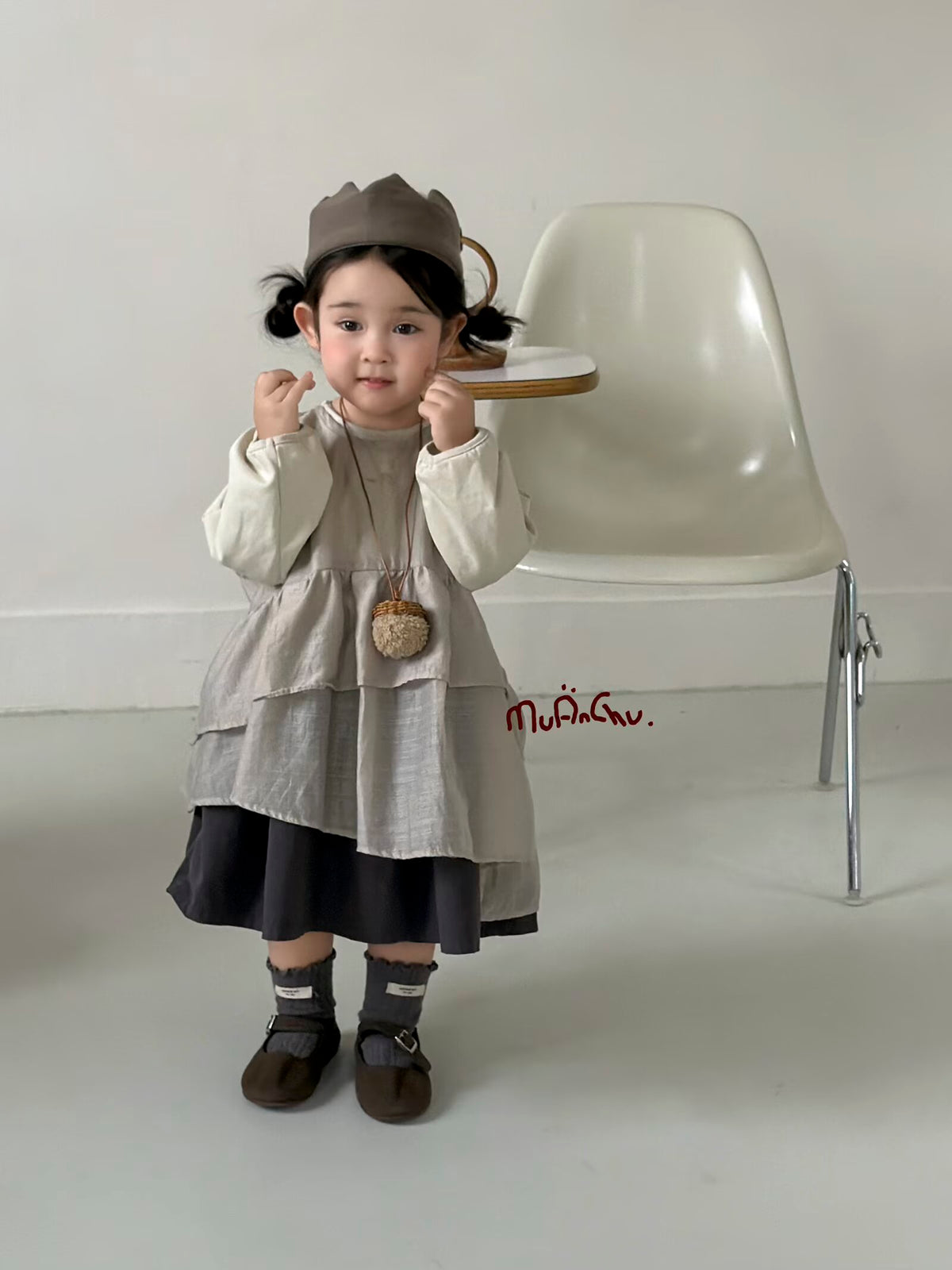 Original styling photo of the taupe layered dress with ivory long-sleeved under-top; hat, necklace, socks and shoes are styling items.