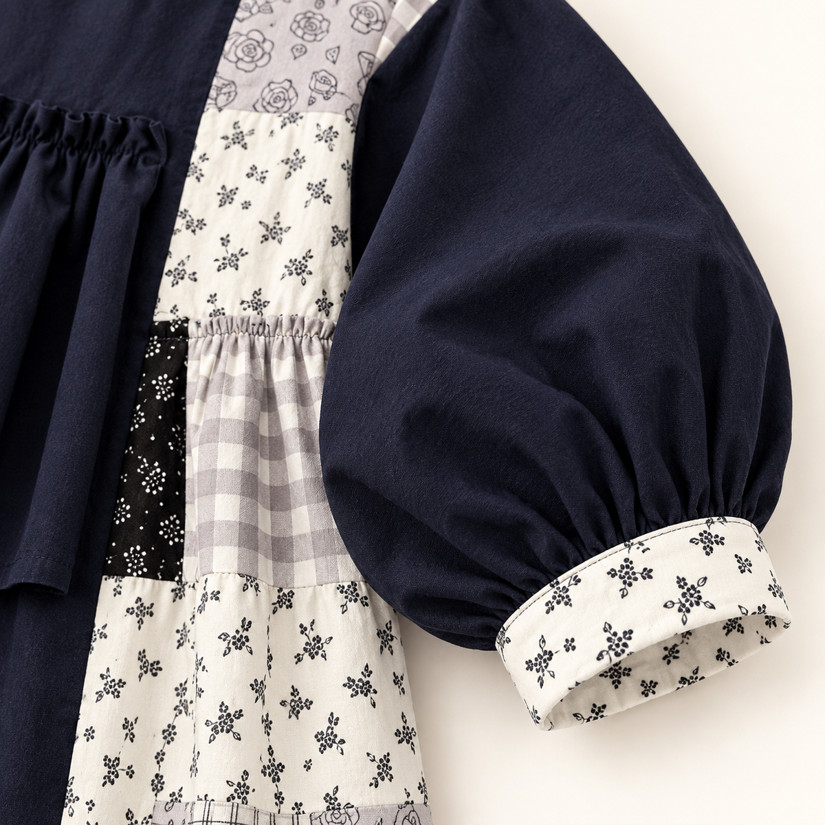 Navy patchwork ruffle dress, floral sleeve cuff detail.