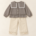 Two-piece outfit with lace collar plaid blouse and cream trousers.